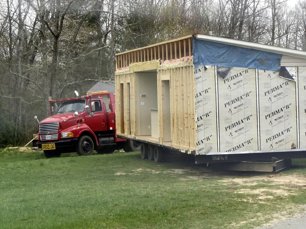 A red truck hauling a home section on a trailer